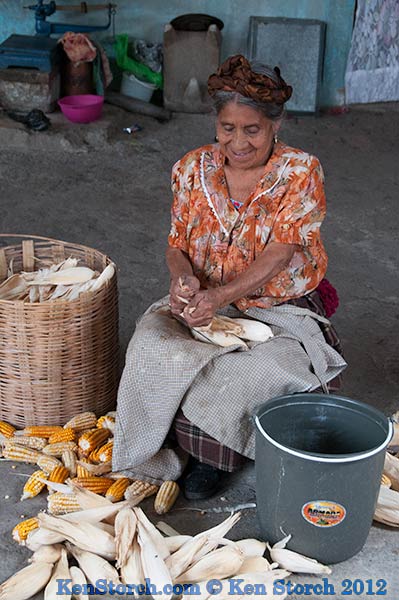 Teresa's mother shucking corn in the back courtyard